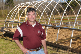 scientist in front of hoop house